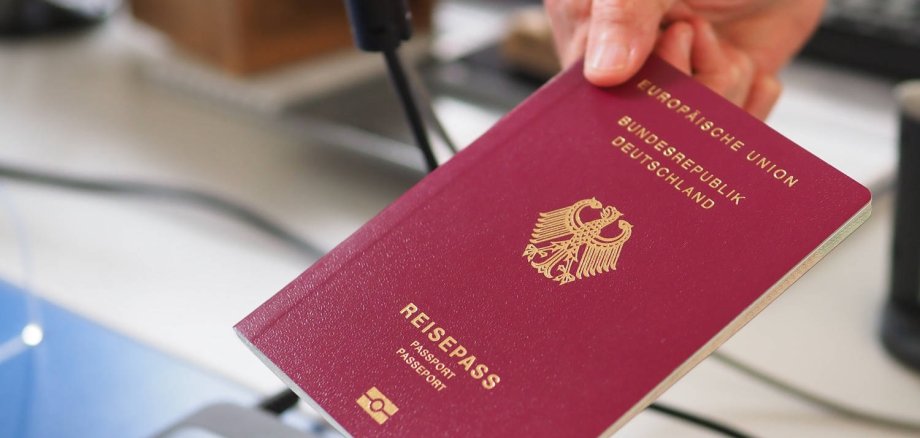 Eine Hand reicht einer anderen Hand einen Reisepass.