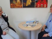Die Gemeindepflegerin Anna Böttger spricht mit einer Seniorin, beide sitzen an einem Tisch.