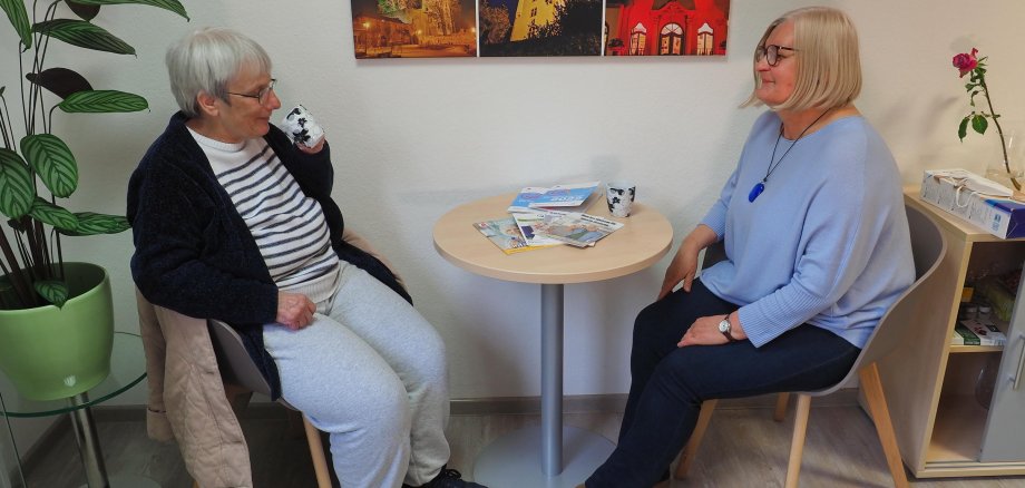 Die Gemeindepflegerin Anna Böttger spricht mit einer Seniorin, beide sitzen an einem Tisch.