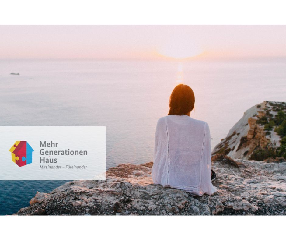 Symbolbild: Frau von Hinten, die auf einem Felsen Richtung Meer blickt