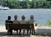 Vier Senioren sitzen auf einer Bank am Rheinufer.