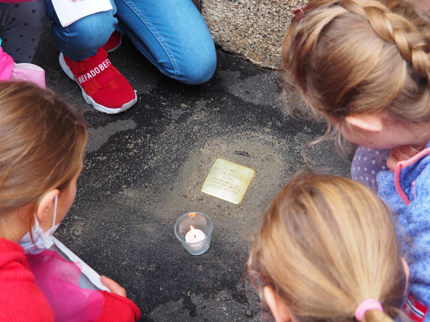 Kinder betrachten den Stolperstein für Magdalena Köhler.