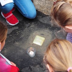Kinder betrachten den Stolperstein für Magdalena Köhler.