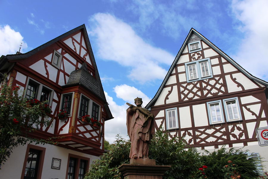 Zwei Fachwerkhäuser, mittig steht eine Statue.