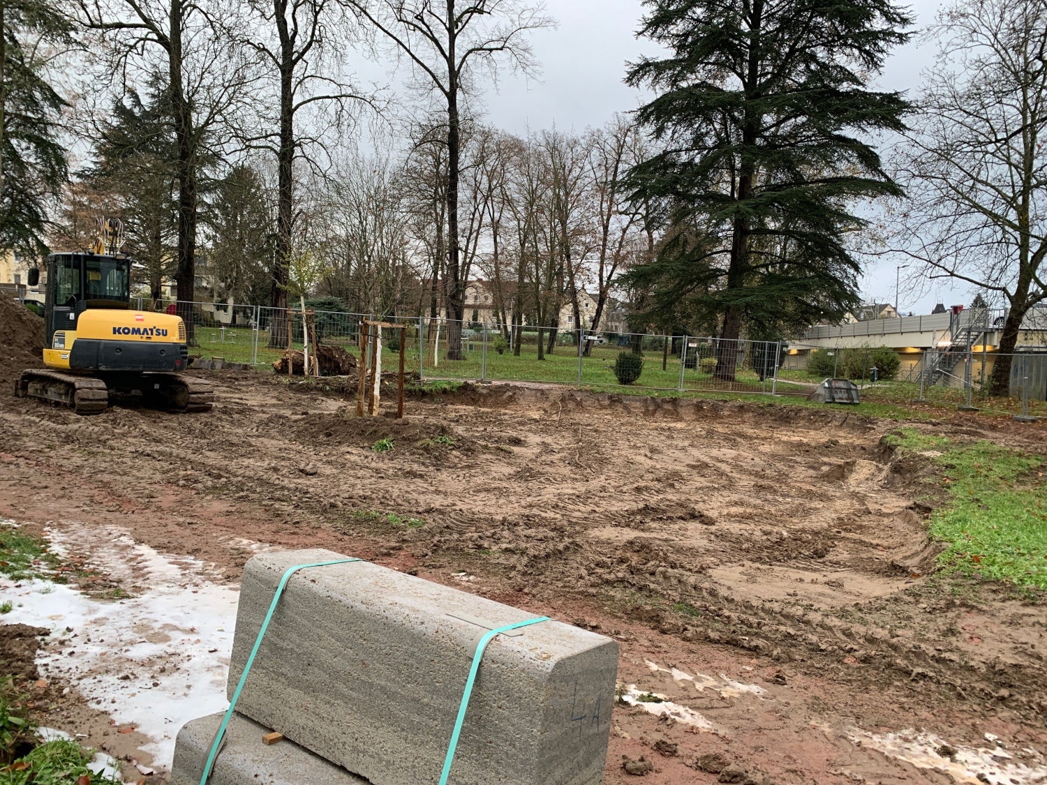 Ein Bagger steht auf einer Erdfläche im Stadtpark, die zuvor ausgebaggert wurde