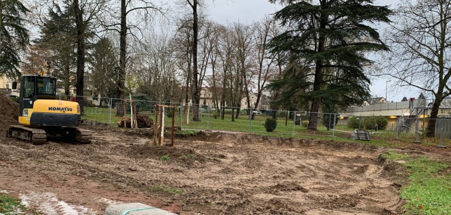 Ein Bagger steht auf einer Erdfläche im Stadtpark, die zuvor ausgebaggert wurde