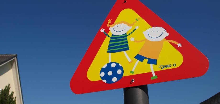 Buntes Straßenschild mit zwei Ballspielenden Kindern.