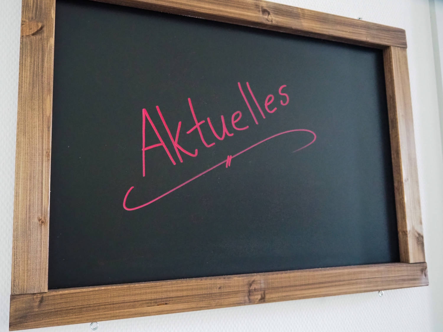 Auf einer schwarzen Tafel steht in rot "Aktuelles" geschrieben.