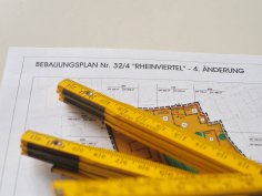 Symbolbild Bebauungspläne Auf einem ausgedruckten Bebauungsplan liegt ein gelber Zollstock.
