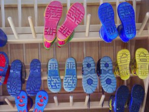 Eltville am Rhein hat mehrere KiTas und auch eine Kindertagespflege. Bunte Kinder-Gummistiefel hängen zum Trocknen auf Holzstäben.