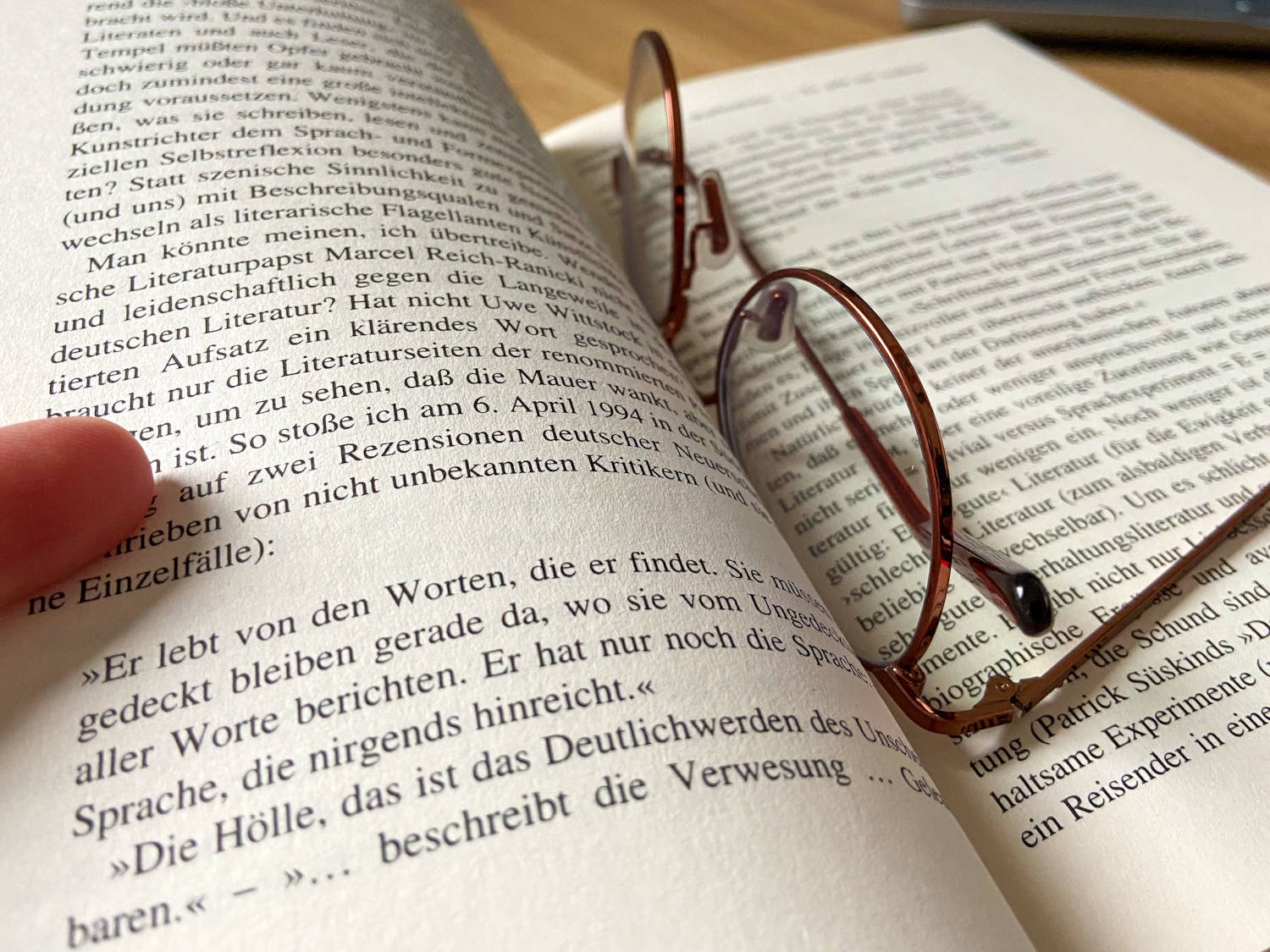 Auf einem aufgeklappten Buch liegt eine Brille.