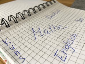 Symbolbild MGH-ANgebot Auf einem karierten Papier stehen die Worte "Mathe, Deutsch, Kunst und Englisch"