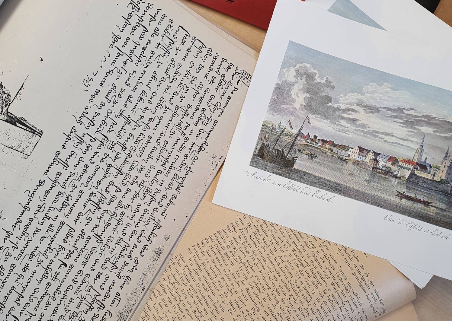 Im Statarchiv der Stadt Eltville werden archivwürdige Unterlagen aus der Verwaltung, Protokollbücher und Rechnungen seit Ende des 18. Jahrhunderts sowie standesamtliche Unterlagen, soweit freigegeben, aus allen Stadtteilen gesammelt. Ein aufgeklapptes Buch, eine Zeichnung und ein Papier mit einer alten Schrift liegen auf einem Tisch.