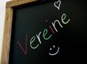 Auf einer schwarzen Tafel steht mit bunter Kreide "Vereine" geschrieben.
