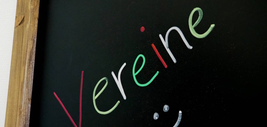 Auf einer schwarzen Tafel steht mit bunter Kreide "Vereine" geschrieben.
