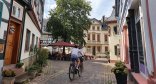 In und um Eltville lässt es sich toll mit dem Rad fahren. Zwei Radfahrer, die man von hinten sieht, radeln durch die Altstadt.