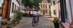 Zwei Radfahrer, die man von hinten sieht, radeln durch die Altstadt.