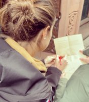 Blick über die Schulter einer Frau, die etwas auf ein Blatt schreibt