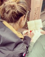 Blick über die Schulter einer Frau, die etwas auf ein Blatt schreibt