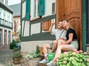 Ein Mann und eine Frau sitzen mit der Walk like a local-Tasche auf Treppenstufen in der Altstadt in Eltville