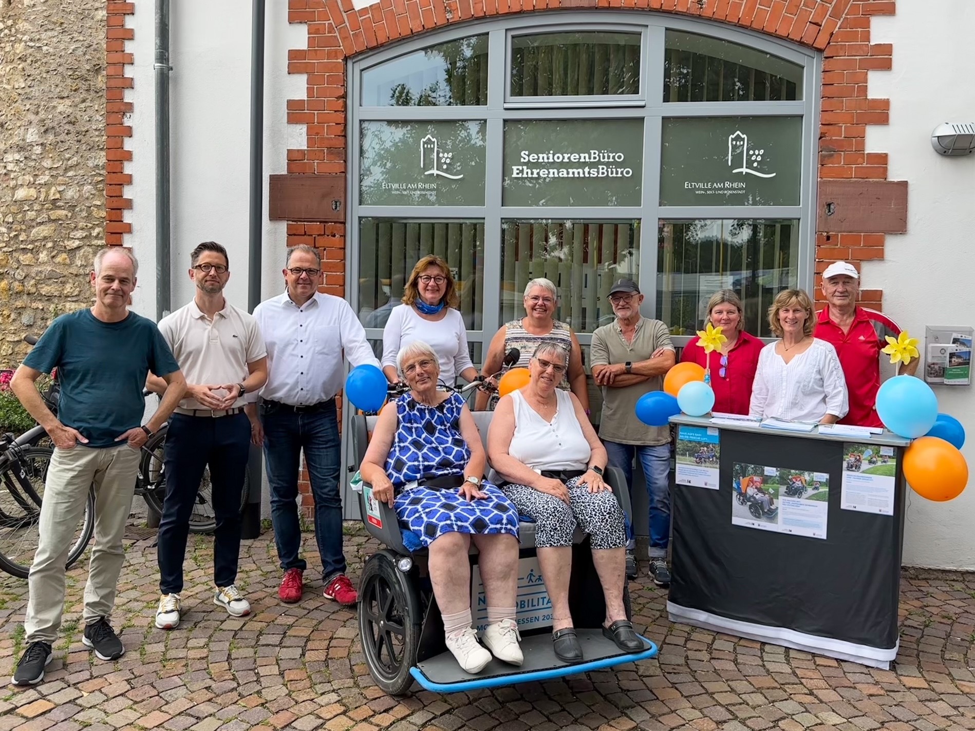 Gruppenfoto mit den Rikscha-Piloten und zwei Seniorinnen in der Rikscha