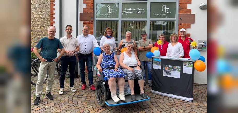 Gruppenfoto mit den Rikscha-Piloten und zwei Seniorinnen in der Rikscha