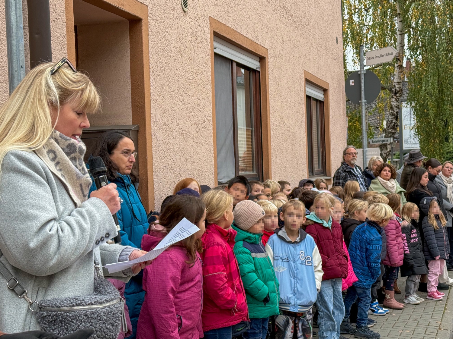 Am linken Rand steht Sabine Gebauer und trägt etwas vor, die Grundschulkinder stehen nebeneinander und hören zu