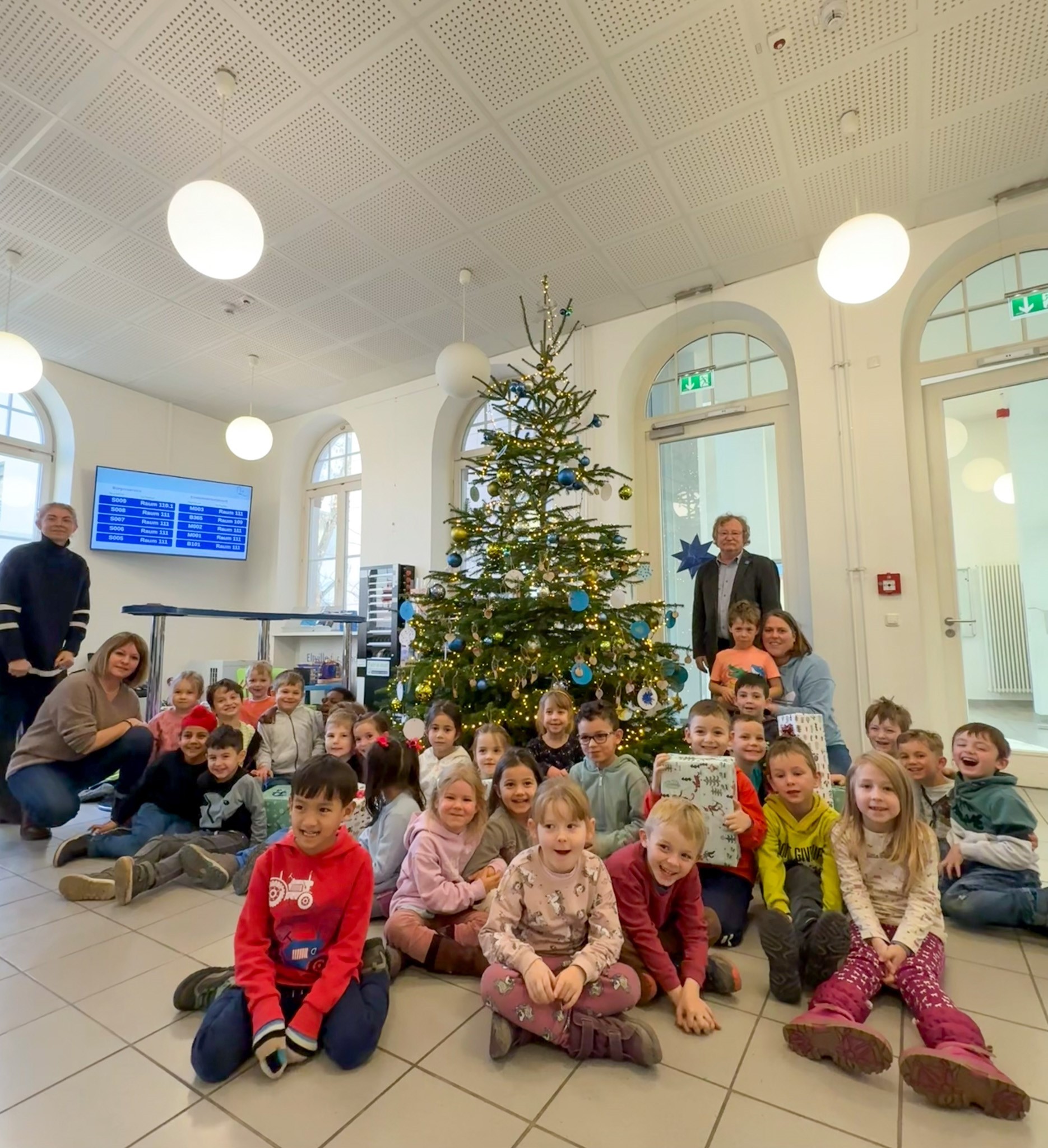 Kitakinder sitzen um den Tannenbaum