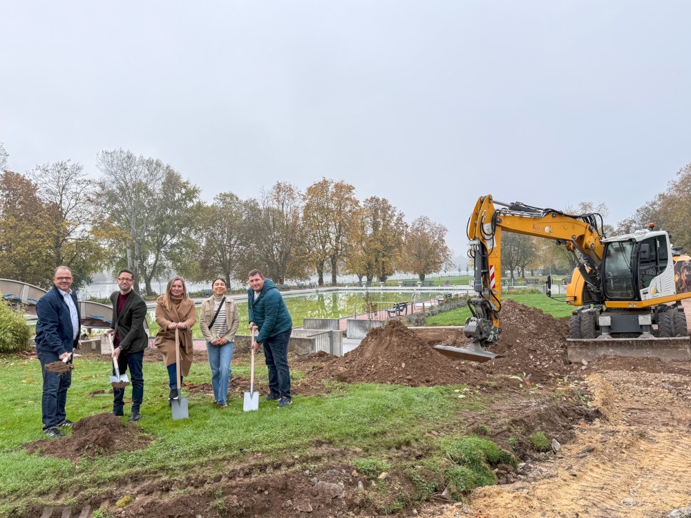 Gruppenfoto mit symbolischen Spatenstich und Bagger im Hintergrund