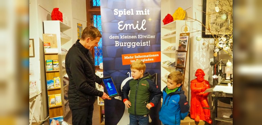 Thomas März hält zwei Jungen das Tablet mit Emil hin