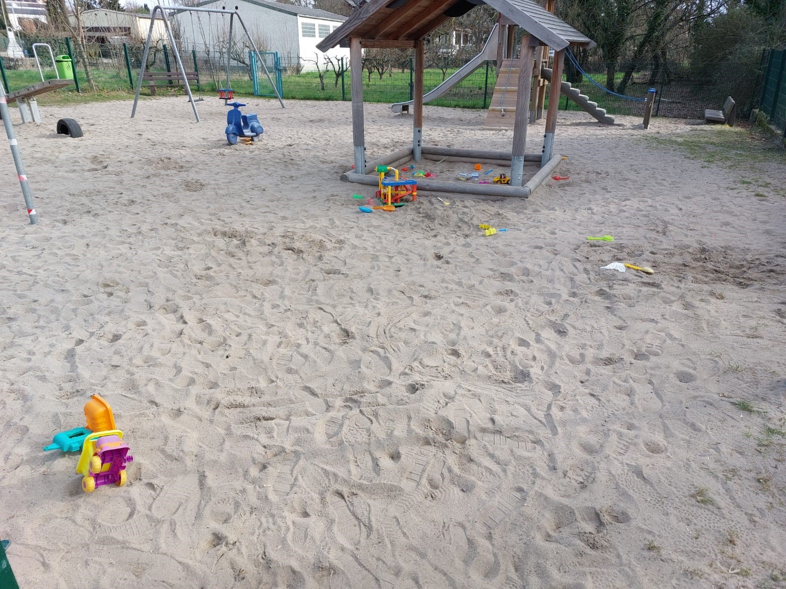 Sandkasten auf einem Spielplatz mit einigen bunten Plastikspielsachen