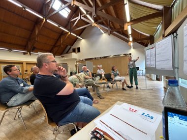 Besucher sitzen und diskutieren, moderiert von der Klimaanpassungsmanagerin