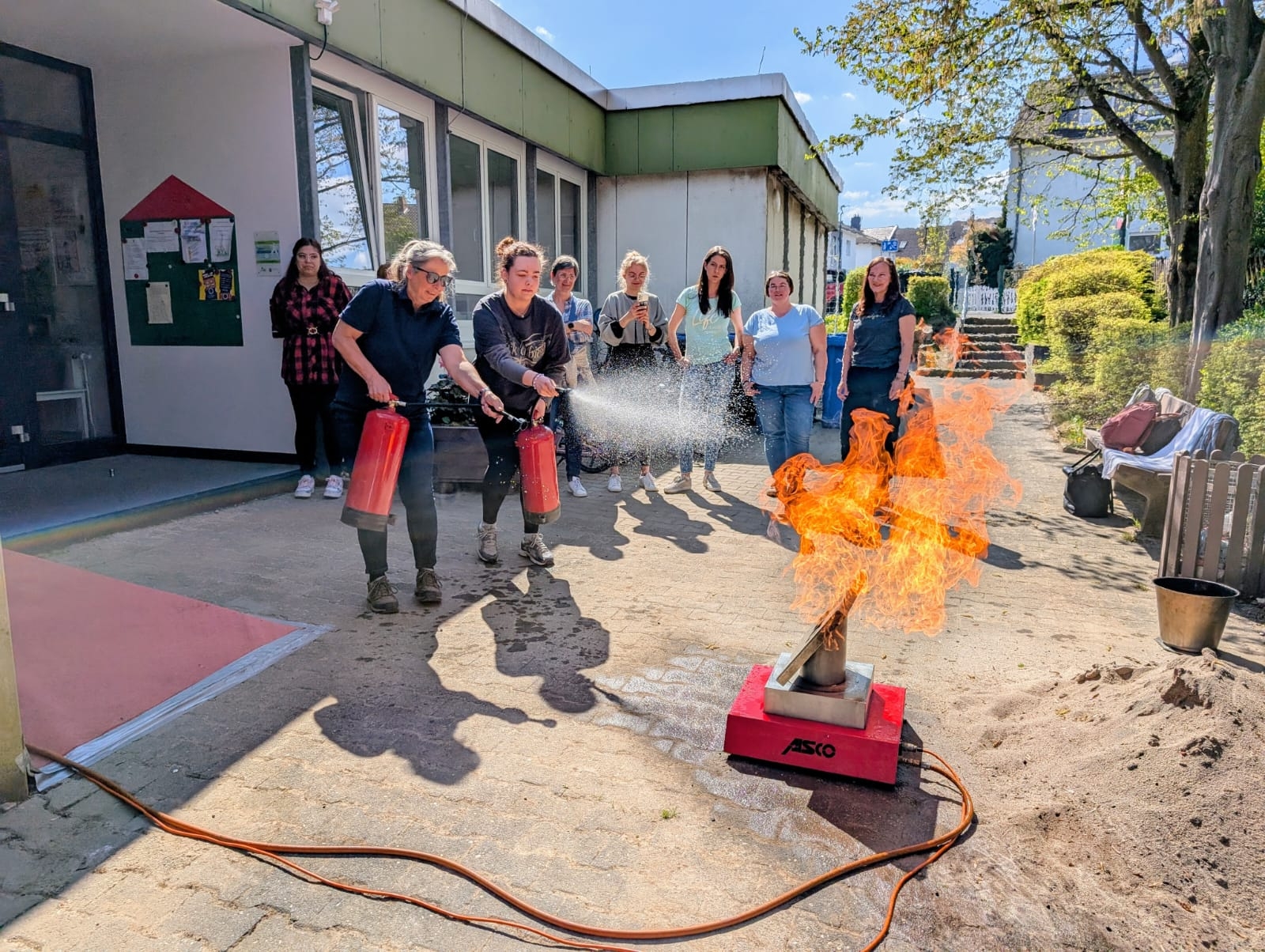 Zwei Mitarbeiterinnen löschen mit Feuerlöscher einen Probebrand