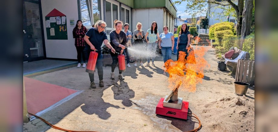 Zwei Mitarbeiterinnen löschen mit Feuerlöscher einen Probebrand