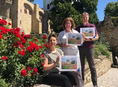 Dier drei Beteiligten mit Puzzle-Kartons vor dem Motiv