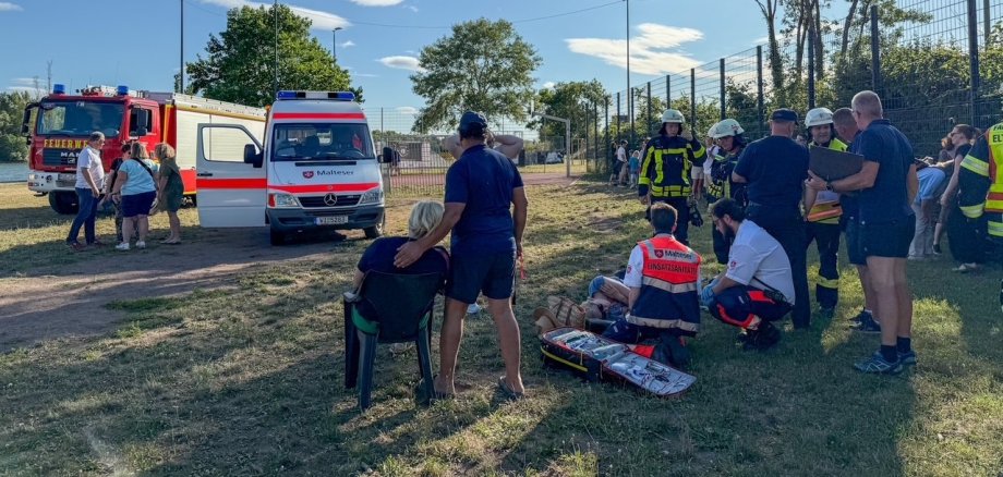 Evakuierte an der Sammelstelle mit Einsatzkräften und Rettungsfahrzeugen