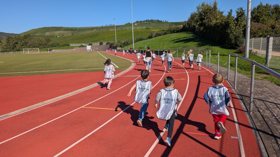 Kinder von hinten zu sehen laufen auf einer Laufbahn
