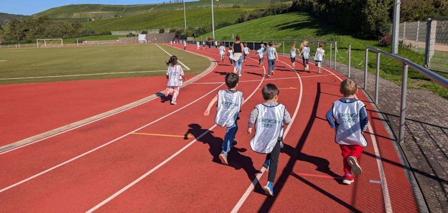 Kinder von hinten zu sehen laufen auf einer Laufbahn