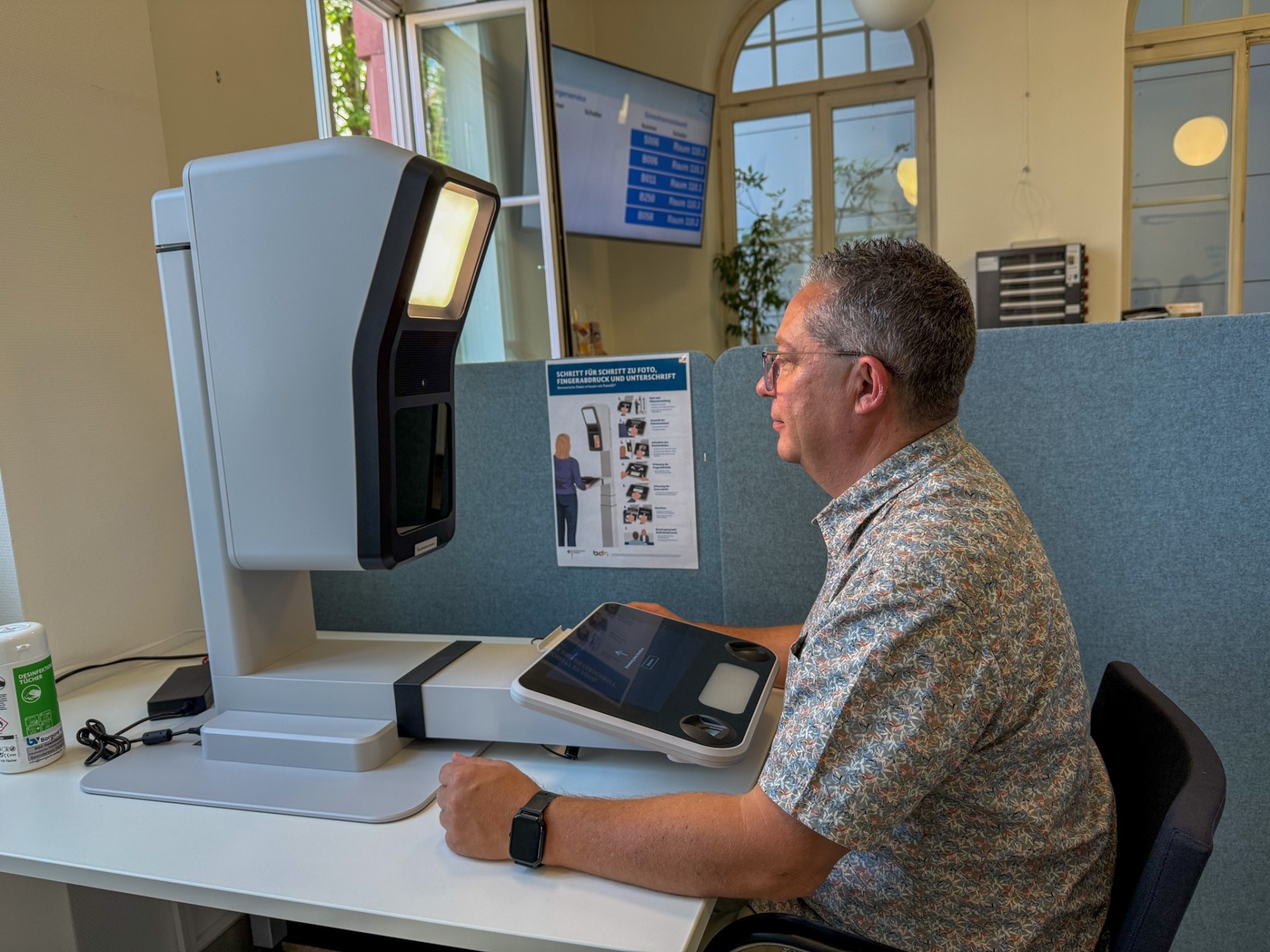 Mann sitzt vor Passfoto-Automat im Eltviller Rathaus