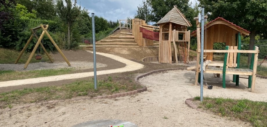 Blick auf dem Spielplatz mit Sandkasten, Kletterturm und Rutschenhügel mit Rutsche