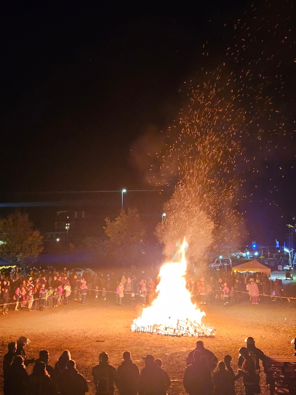 Martinsfeuer mit Besuchern, die um das abgesperrte Feuer stehen
