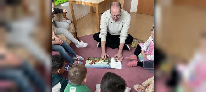 Ingo Schon beim Vorlesen, die Kinder sitzen im Kreis um ihn herum
