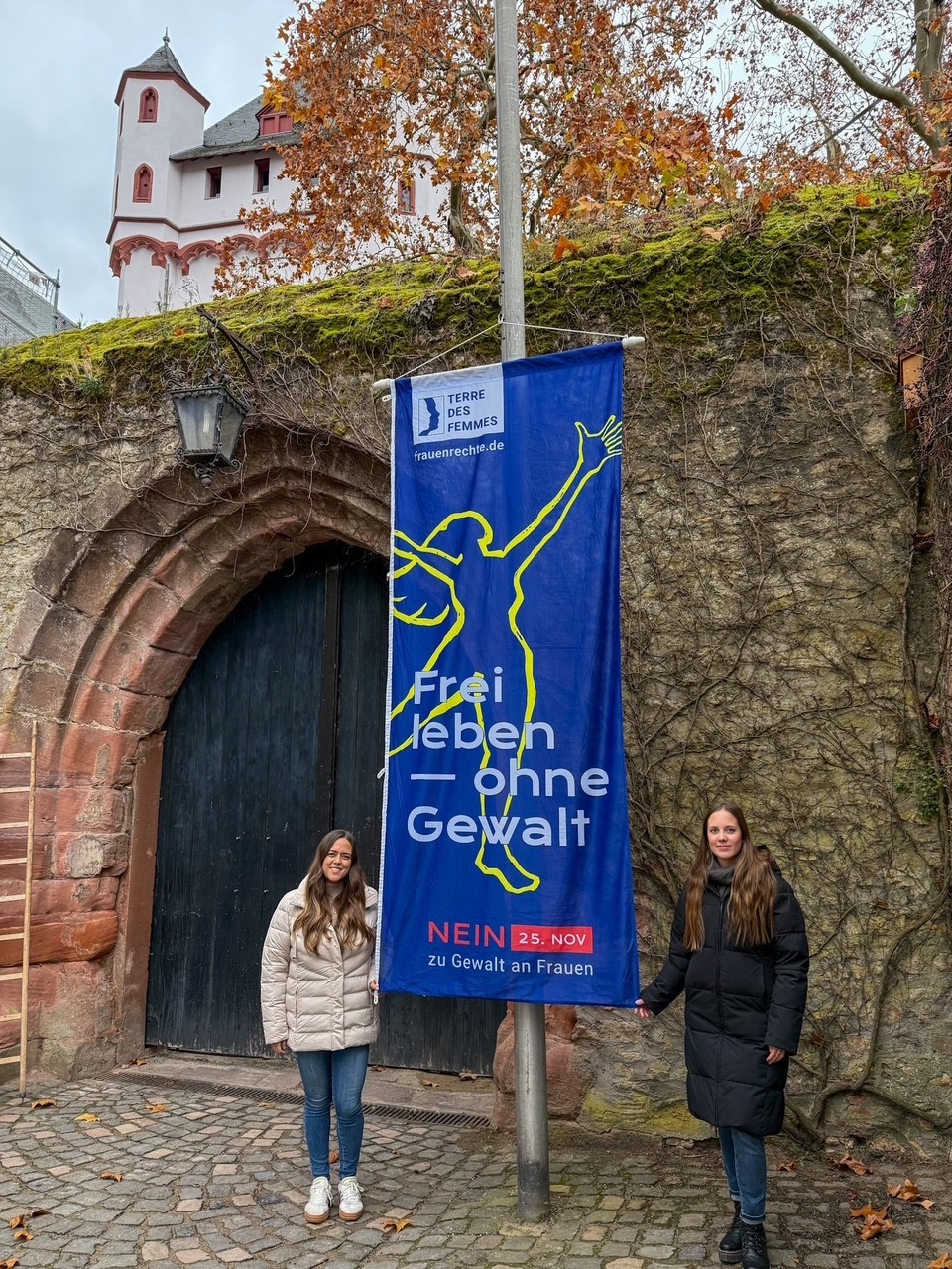 Die beiden Frauenbeauftragten vor der Burg mit gehisster Flagge "Nein gegen Gewalt an Frauen"