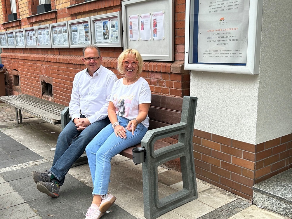 Bürgermeister und Ladenbesitzerin testen die neuen Bänke