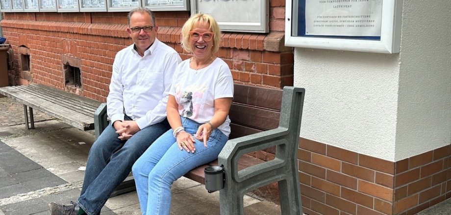 Bürgermeister und Ladenbesitzerin testen die neuen Bänke