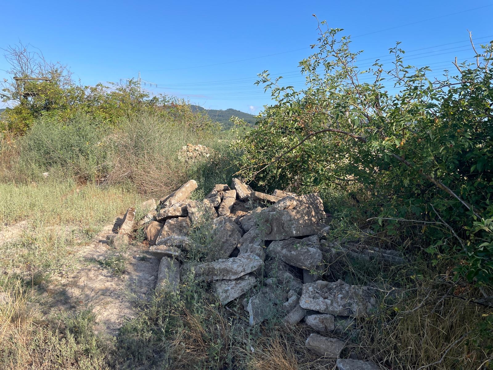 Abrissmaterial einer Mauer liegt verloren in der Landschaft