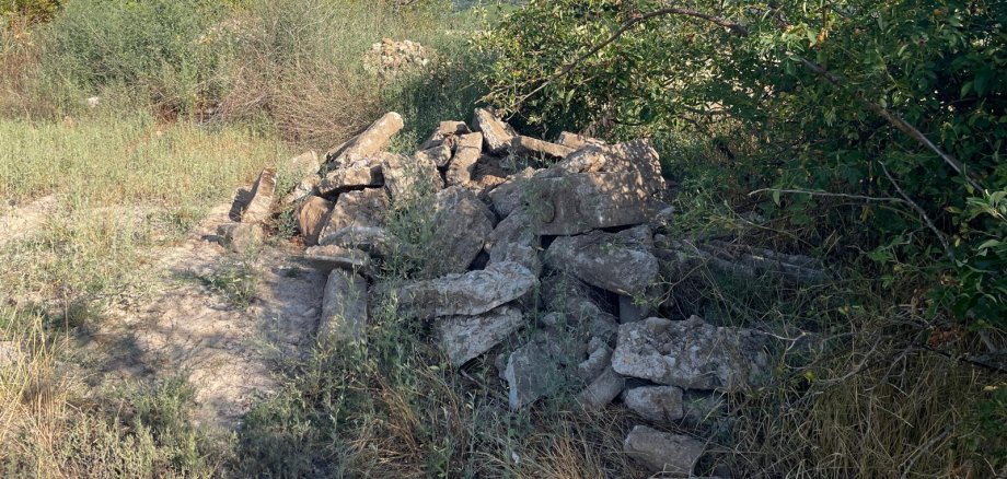 Abrissmaterial einer Mauer liegt verloren in der Landschaft