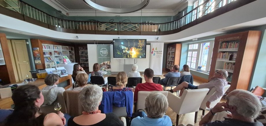 Menschen von hinten fotografiert, gucken einen Film im Lesesaal