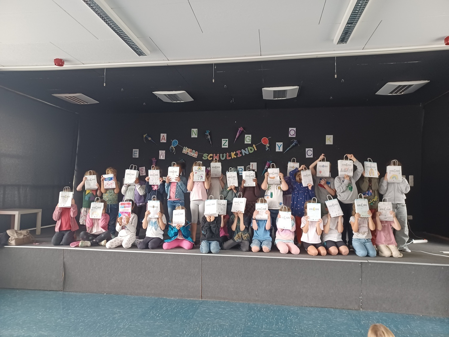 Schulkinder mit den bunten Tüten vor den Gesichtern auf einem Gruppenfoto