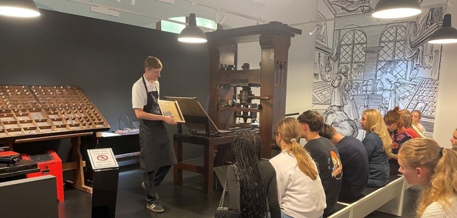 Schulklasse von hinten schaut bei Druckvorführung zu